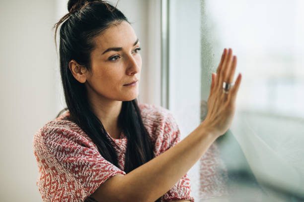 istock Young thoughtful woman touching the window during rainy day. 1128873530