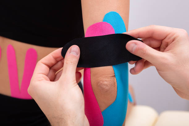 istock Physiotherapist Applying Kinesiology Tape On Patient's Elbow 1128875577