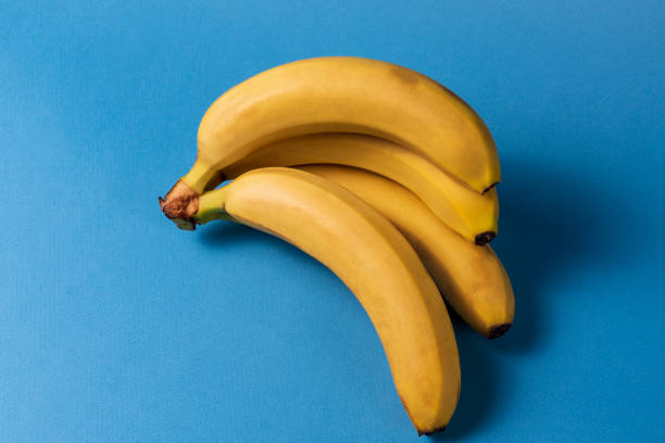 istock Minimalism style. Fruit pattern with yellow ripe banana fruit over blue background. 1128876386