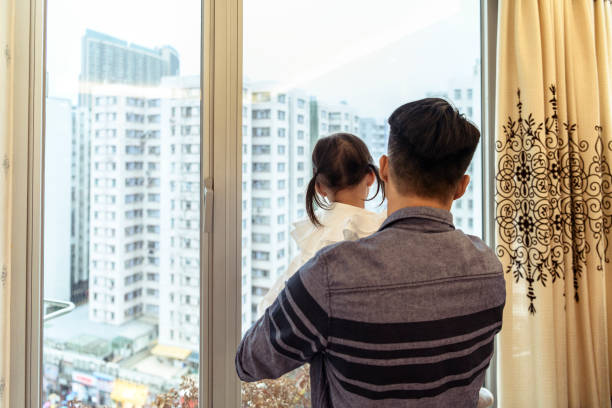 istock Father and daughter looking out of window 1128876474