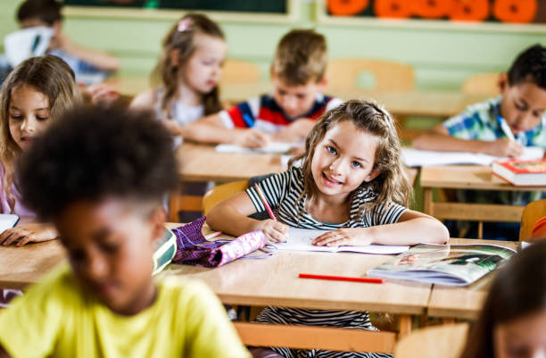 istock Happy schoolgirl writing a dictation during a class in elementary school. 1128876812