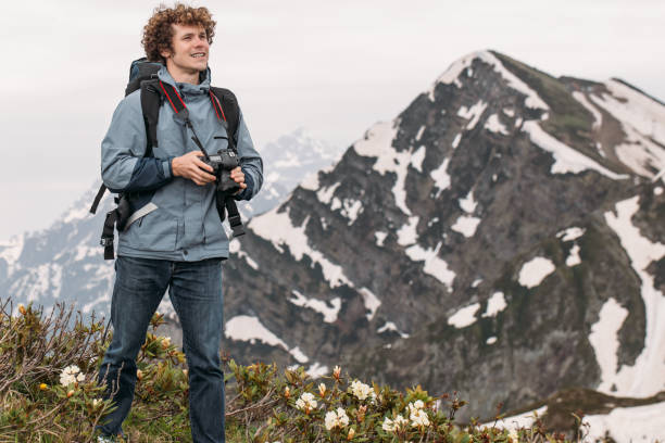 istock cheerful backpacker is holding his digital camera while standing on the hill 1128876966