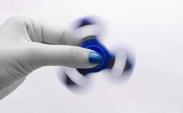 Photo of Blue thumb nail and fidget spinner and the rest of photography black-and white. Popular toy.
