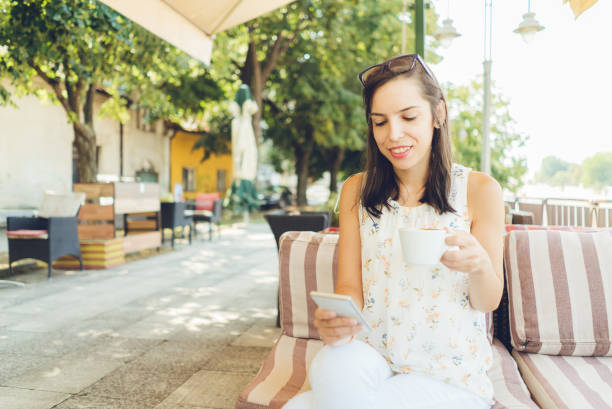 istock Girl using her smartphone and drink coffee outdoor 1128878331