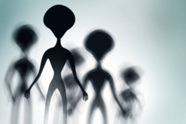 istock Silhouettes of spooky aliens and bright light on behind them 1128878613