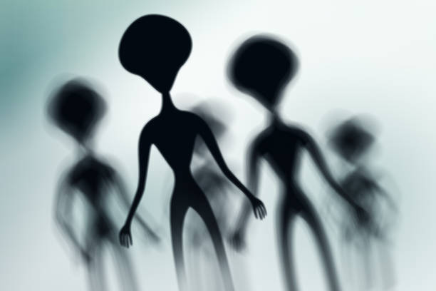 istock Silhouettes of spooky aliens and bright light on behind them 1128878636