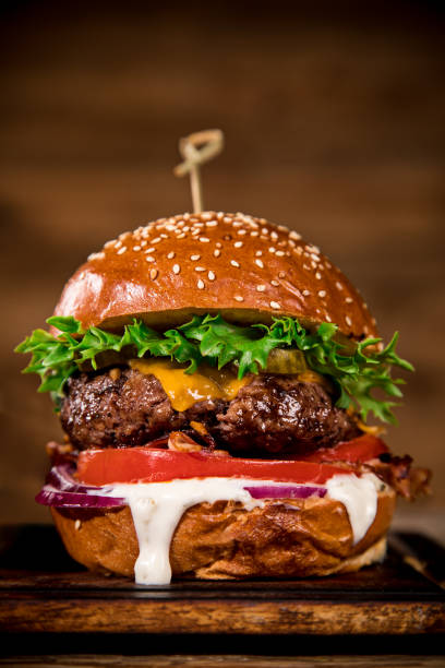 istock Tasty burger on wooden table. 1128882373