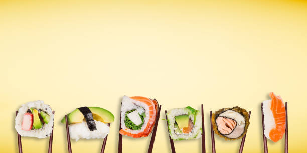istock Traditional japanese sushi pieces placed between chopsticks, separated on pastel background. 1128884331