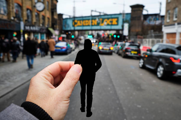 silhouette of a man by Camden Town, in London, UK closeup of the hand of a caucasian man holding a paper cutout in the shape of a young man, wearing a hood, walking by the popular Camden High Street, in London, United Kingdom camden lock stock pictures, royalty-free photos & images