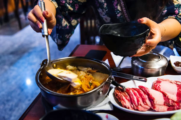 istock Woman taking spicy sausage stew 1128885127