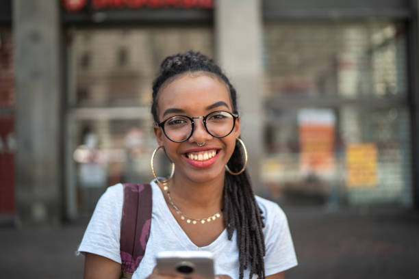 afro jeune femme dans la ville à l’aide de portrait de smartphone - mode de vie alternatif photos et images de collection