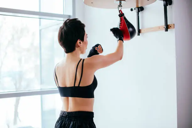 rear view shot of energetic female practising boxing punches at gym on the panoramic background. concept of active workout