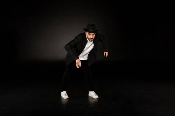 istock Young male modern dancer in black clothes and hat 1128886244