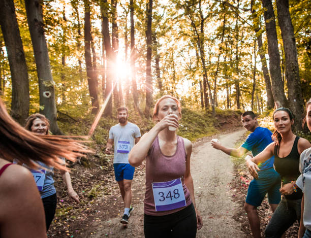 istock Athletic woman taking refreshment during marathon race in the forest. 1128890122