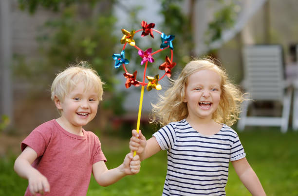 男の子と女の子の散歩中に楽しんでいます。風車のある幸せな子。 - fun walk ストックフォトと画像