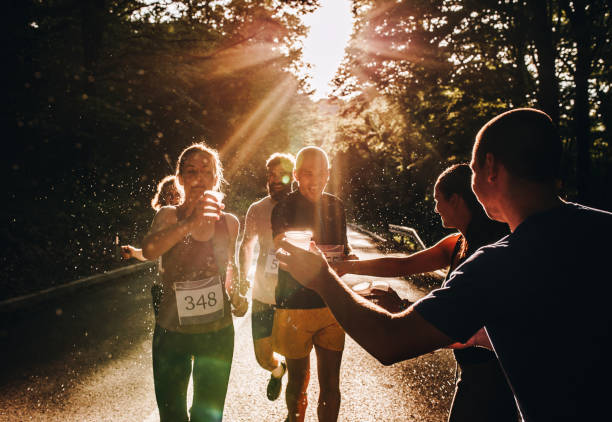 istock Marathon runners taking water from volunteers during a race at sunset. 1128891538