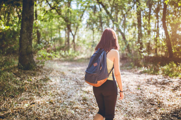 istock Traveler woman with backpack walking in forest. 1128891689