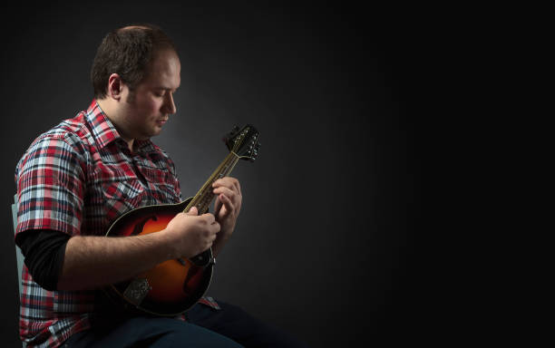 istock Male musician sits and plays a lute. 1128891728