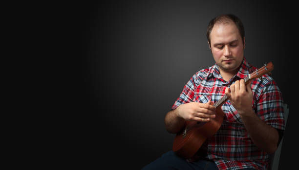 istock Male musician sits and plays a ukulele. 1128891731