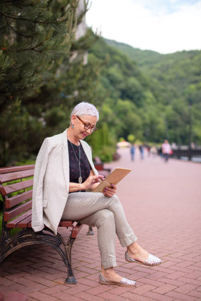 istock stylish attractive mature woman using the touch pad on holiday 1128892600
