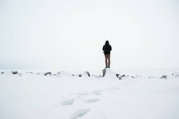 istock Man with backpack standing in mountains. Cold weather, snow on hills. 1128893144