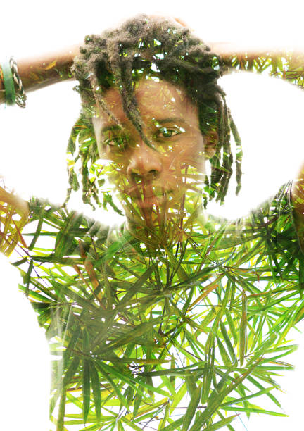 istock Double exposure of a dark skinned man with dreadlocks and hands behind head combined with a photograph of lush, green tropical plants 1128893184