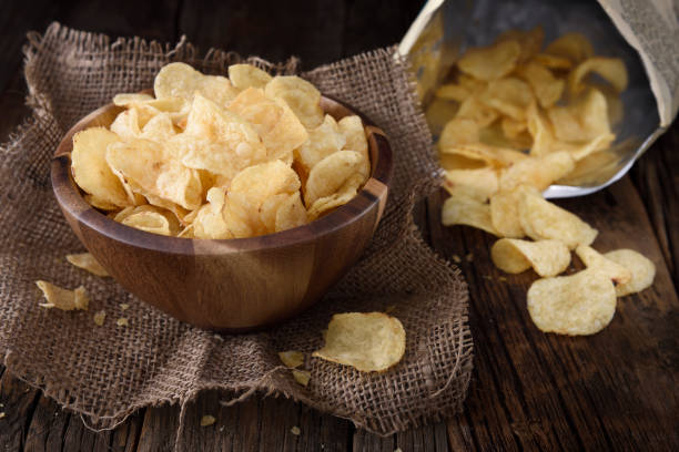 Potato chips Classic or regular potato chips bag with chips in a wooden bowl fried potato stock pictures, royalty-free photos & images