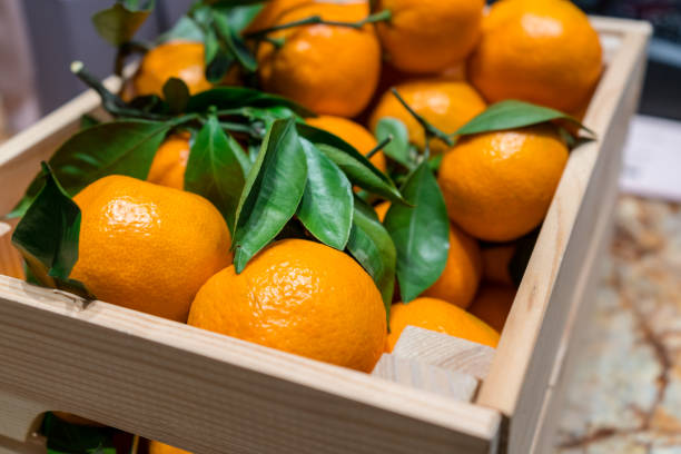 istock Fresh mandarins with green leafs in the box 1128897467