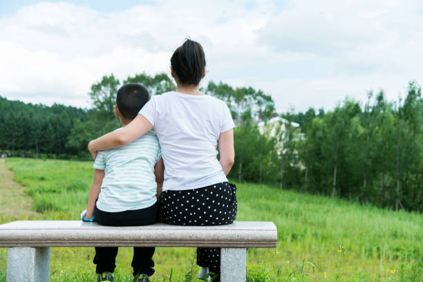 istock Mother and son sitting on park bench 1128900869