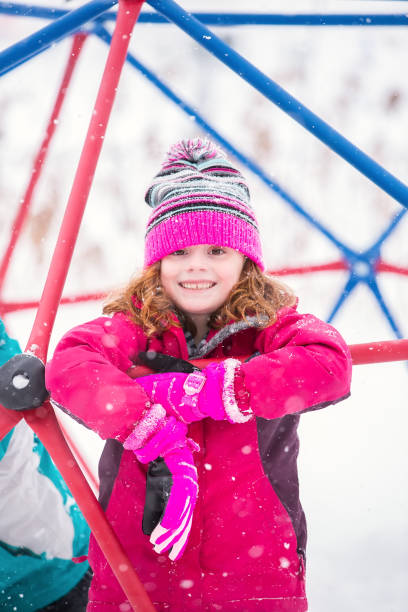 istock Girl Playing on Jungle Gym During Snow Storm 1128901163