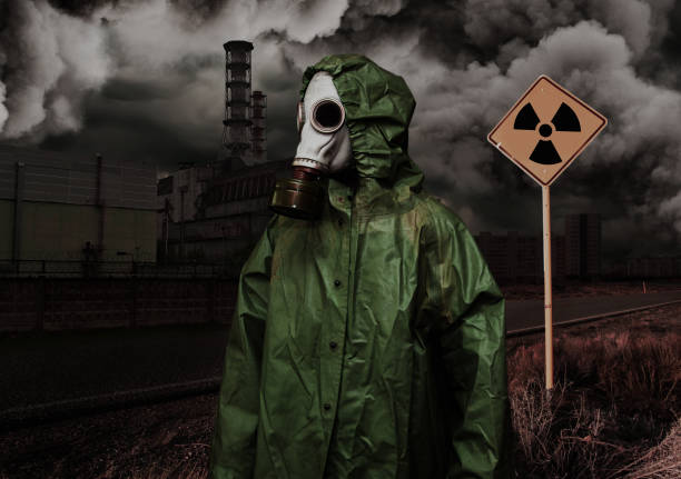 Man in gas mask and cloak of chemical protection on abandoned road. Man in gas mask and cloak of chemical protection on abandoned road in front of Nuclear station. Nuclear pollution concept cape garment photos stock pictures, royalty-free photos & images