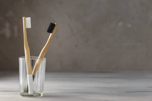 duas escovas de dente de bambu amigável eco em um vidro - toothbrush dental hygiene glass dental equipment - fotografias e filmes do acervo