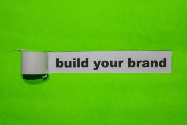 Photo of Build Your Brand, Inspiration and business concept on green torn paper