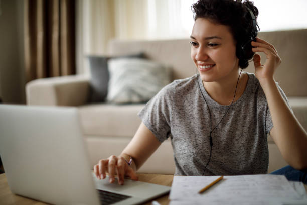 giovane donna che usa laptop e ascolta musica a casa - music listening child smiling foto e immagini stock