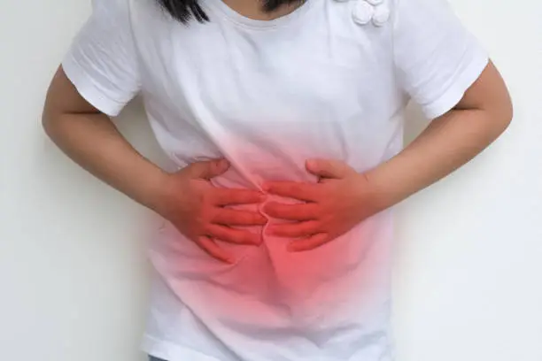 Photo of Woman Child's hands on her stomach with red spot as suffering on stomachache. Girl school kid suffer from Chronic Diarrhea,Digestive Disorders, stomach pain,Crohnâs Disease, irritable bowel syndrome