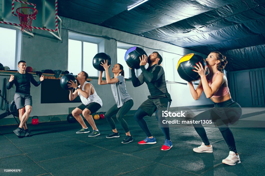 functional fitness workout at the gym with medicine ball Functional fitness workout at the gym with medicine ball. The group of young people during training session. Fit athletic men and women at health club. Healthy lifestyle concept Earth's Core Stock Photo