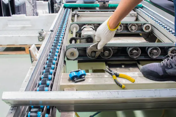 Photo of worker maintenance and repair conveyor belt in factory