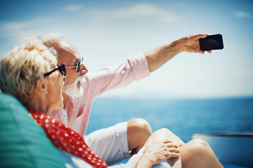 Senior couple on the sailing boat cruise taking selfie to remember this beautiful moment that they enjoy together.