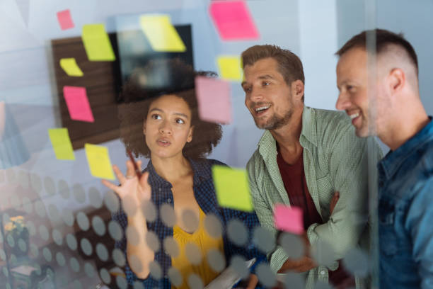 istock Coworkers discussing new ideas on a glass wall 1128910882