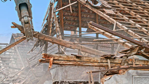 Excavator pulling long wooden beams of an old house being torn down.