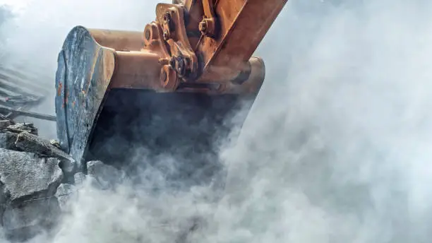 Excavator demolishing wall of an old house.