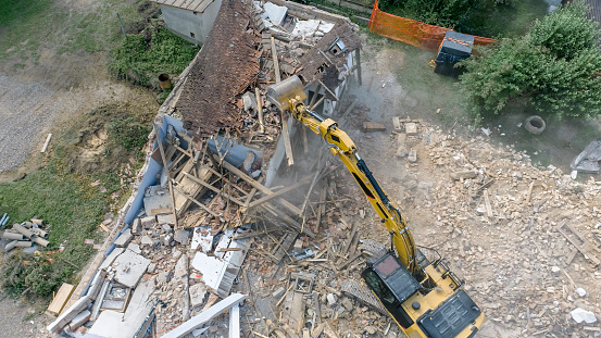 Excavator demolishing old house.