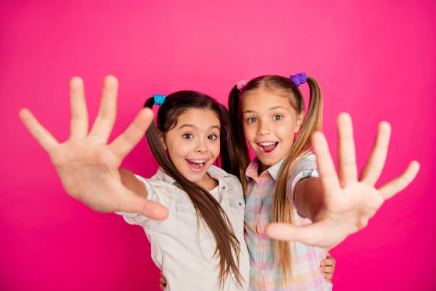 foto ravvicinata due piccole età lei le sue ragazze mani palmi delle braccia contando le dita lezione di matematica lezione di classe felice indossando jeans casual jeans a scacchi plaid camicie isolate rosa vibrante sfondo vivido - 10 11 anni foto e immagini stock