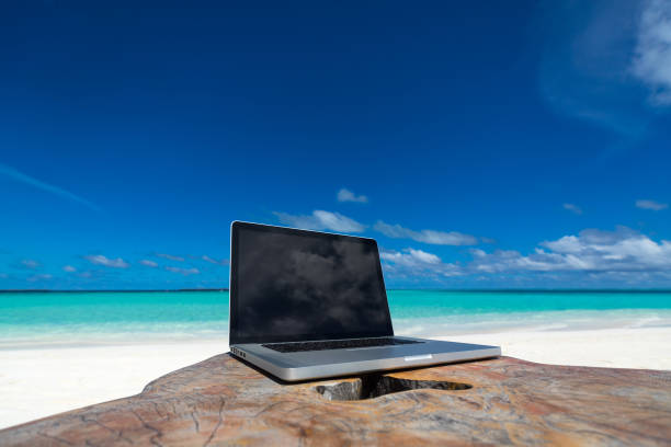 istock laptop blank screen on wooden desk with beach. relax concept. 1128914140