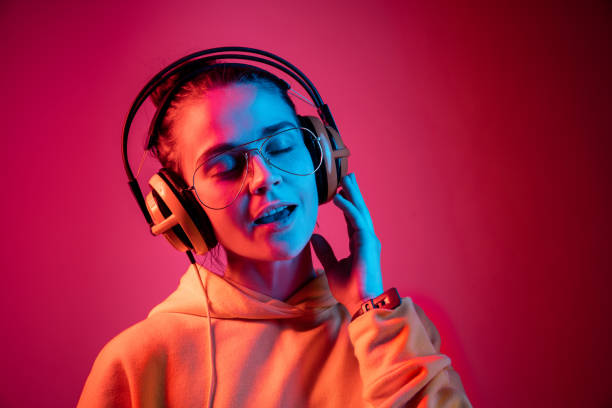 fashion pretty woman with headphones listening to music over neon background - young adult technology beautiful singing imagens e fotografias de stock