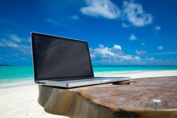 istock laptop blank screen on wooden desk with beach. relax concept. 1128915321