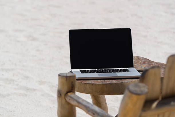 istock laptop blank screen on wooden desk with beach. relax concept. 1128915339
