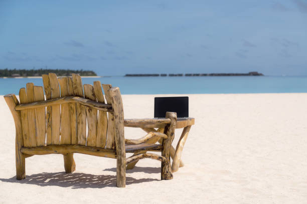 istock laptop blank screen on wooden desk with beach. relax concept. 1128915344
