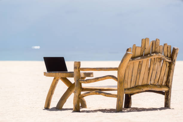 istock laptop blank screen on wooden desk with beach. relax concept. 1128915346