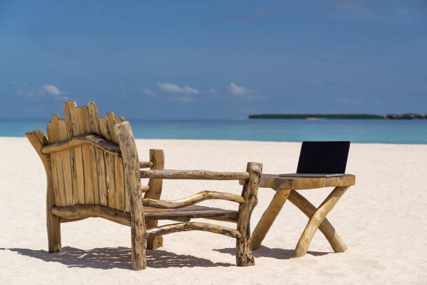 istock laptop blank screen on wooden desk with beach. relax concept. 1128915347